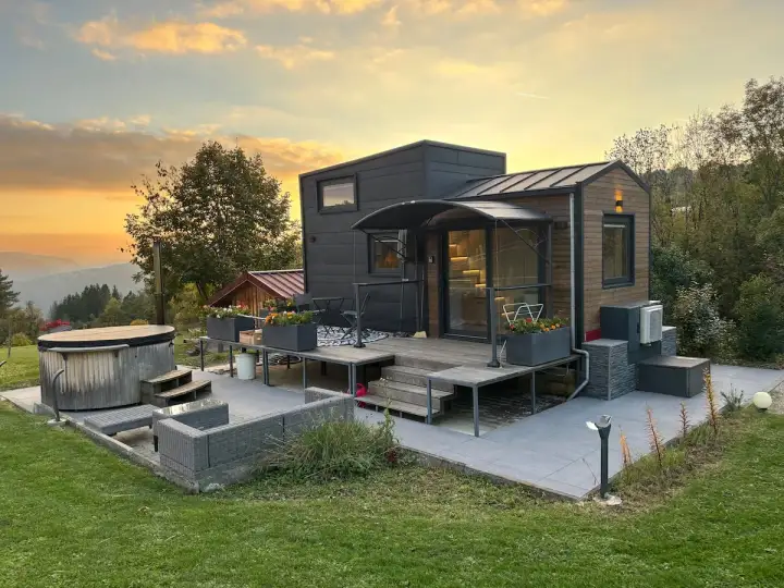 Tiny house dans le Jura, avec jacuzzi et mobilier extérieur, au coucher du soleil.